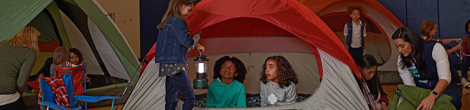  Two daisy Girl Scouts holding lantern in tent wearing trefoil shirt 
